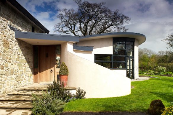 front view of contemporary house with curved walls and green lawn